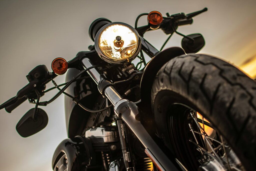 Dramatic close-up of a classic motorcycle's headlight with a low angle view at sunset.